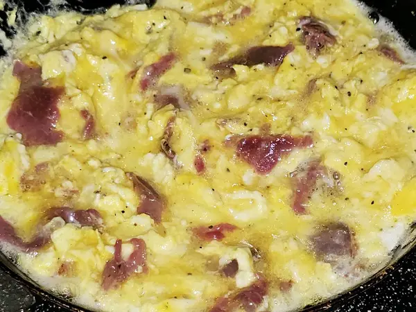 Scrambled eggs with pastrami, a dish made from eggs stirred, whipped or beaten together while being gently heated, with salt, butter, oil and black pepper with slices and pieces of beef pastrami