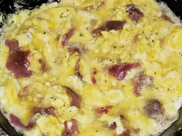 Scrambled eggs with pastrami, a dish made from eggs stirred, whipped or beaten together while being gently heated, with salt, butter, oil and black pepper with slices and pieces of beef pastrami