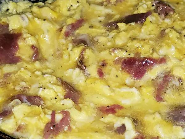 Scrambled eggs with pastrami, a dish made from eggs stirred, whipped or beaten together while being gently heated, with salt, butter, oil and black pepper with slices and pieces of beef pastrami
