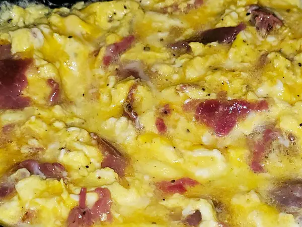 Scrambled eggs with pastrami, a dish made from eggs stirred, whipped or beaten together while being gently heated, with salt, butter, oil and black pepper with slices and pieces of beef pastrami