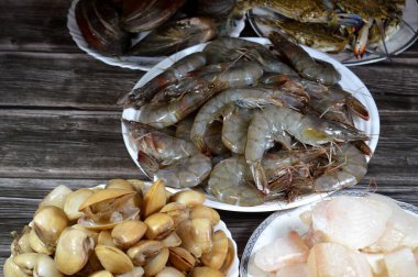 Çeşitli çiğ karides, midye, taze yengeç, balık filetosu ve midye çeşitleri, çeşitli mutfaklarda kullanılabilecek çeşitli deniz ürünleri, balık parçaları, midye, karides ve yengeç.