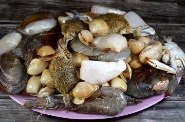 Çeşitli çiğ karides, midye, taze yengeç, balık filetosu ve midye çeşitleri, çeşitli mutfaklarda kullanılabilecek çeşitli deniz ürünleri, balık parçaları, midye, karides ve yengeç.