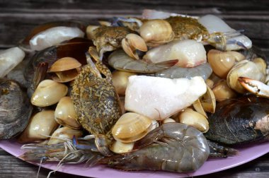 Çeşitli çiğ karides, midye, taze yengeç, balık filetosu ve midye çeşitleri, çeşitli mutfaklarda kullanılabilecek çeşitli deniz ürünleri, balık parçaları, midye, karides ve yengeç.