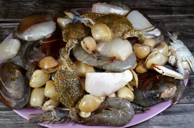 Çeşitli çiğ karides, midye, taze yengeç, balık filetosu ve midye çeşitleri, çeşitli mutfaklarda kullanılabilecek çeşitli deniz ürünleri, balık parçaları, midye, karides ve yengeç.