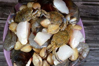 Çeşitli çiğ karides, midye, taze yengeç, balık filetosu ve midye çeşitleri, çeşitli mutfaklarda kullanılabilecek çeşitli deniz ürünleri, balık parçaları, midye, karides ve yengeç.