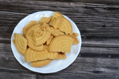 Tahta arka planda bir tabak sade bisküvi, un ve tereyağından yapılmış bisküvi, çay saatinde ya da atıştırmalık olarak, ağız sulandıran kurabiyeler.