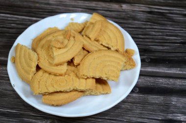 Tahta arka planda bir tabak sade bisküvi, un ve tereyağından yapılmış bisküvi, çay saatinde ya da atıştırmalık olarak, ağız sulandıran kurabiyeler.