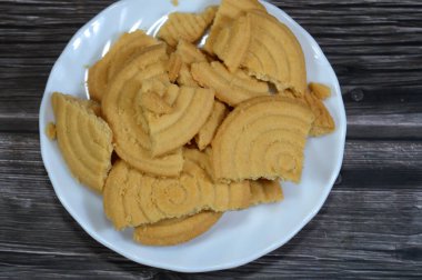 Tahta arka planda bir tabak sade bisküvi, un ve tereyağından yapılmış bisküvi, çay saatinde ya da atıştırmalık olarak, ağız sulandıran kurabiyeler.