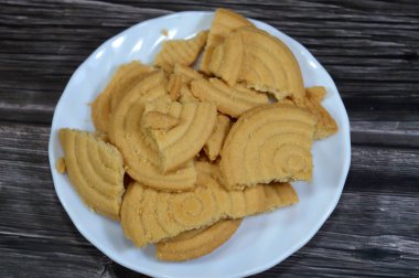 Tahta arka planda bir tabak sade bisküvi, un ve tereyağından yapılmış bisküvi, çay saatinde ya da atıştırmalık olarak, ağız sulandıran kurabiyeler.
