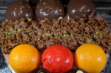 Dondurmalı pasta, üzerinde çikolata topu ve krema, karamel sosu, fındıklı çikolata parçaları, fındık, mango ve çilek topları, yaz ve tatil konsepti.