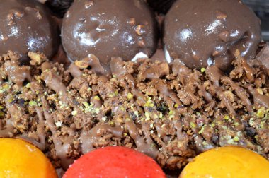 Dondurmalı pasta, üzerinde çikolata topu ve krema, karamel sosu, fındıklı çikolata parçaları, fındık, mango ve çilek topları, yaz ve tatil konsepti.