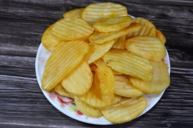 Patates cipsi, cips, ince patates dilimleri, kızartılmış, pişirilmiş, veya kızarana kadar havada kızartılmış, aperatif, meze veya meze olarak servis edilmiş, temel cips pişti ve tuzlandı, bazıları diğer tatlarla birlikte.