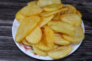 Patates cipsi, cips, ince patates dilimleri, kızartılmış, pişirilmiş, veya kızarana kadar havada kızartılmış, aperatif, meze veya meze olarak servis edilmiş, temel cips pişti ve tuzlandı, bazıları diğer tatlarla birlikte.