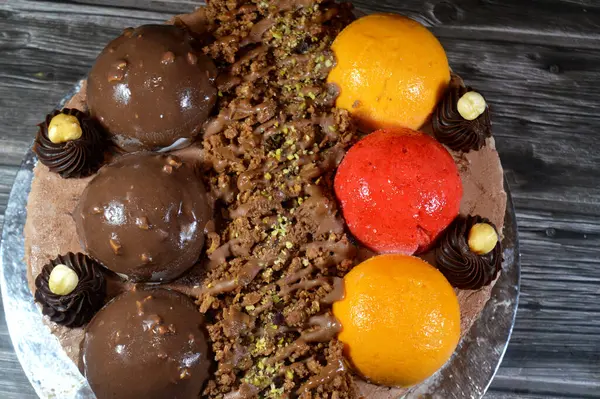 Dondurmalı pasta, üzerinde çikolata topu ve krema, karamel sosu, fındıklı çikolata parçaları, fındık, mango ve çilek topları, yaz ve tatil konsepti.