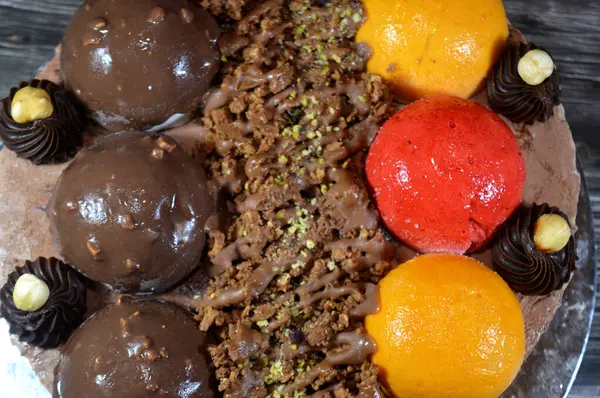 Dondurmalı pasta, üzerinde çikolata topu ve krema, karamel sosu, fındıklı çikolata parçaları, fındık, mango ve çilek topları, yaz ve tatil konsepti.