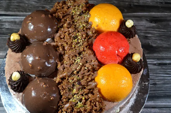 Dondurmalı pasta, üzerinde çikolata topu ve krema, karamel sosu, fındıklı çikolata parçaları, fındık, mango ve çilek topları, yaz ve tatil konsepti.