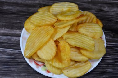 Patates cipsi, cips, ince patates dilimleri, kızartılmış, pişirilmiş, veya kızarana kadar havada kızartılmış, aperatif, meze veya meze olarak servis edilmiş, temel cips pişti ve tuzlandı, bazıları diğer tatlarla birlikte.