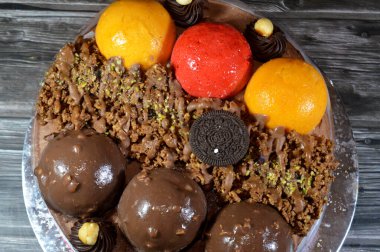 Kahire, Mısır, Haziran 12025: Kremalı pasta, üzerinde Oreo, çikolata topları ve krema, fındık ve karamel sosu ve çikolata, fındık, çilek ve mango topları var.