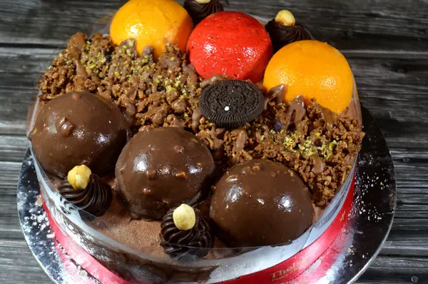 Kahire, Mısır, Haziran 12025: Kremalı pasta, üzerinde Oreo, çikolata topları ve krema, fındık ve karamel sosu ve çikolata, fındık, çilek ve mango topları var.