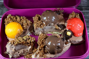 Bir parça dondurmalı kek, üzerinde çikolata topu ve krema, karamel sosu, fındıklı çikolata parçaları, fındıklı fındık, mango ve çilekli toplar, yaz ve tatil kavramı.