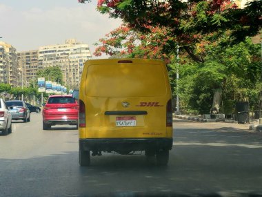 Kahire, Mısır, 31 Mayıs 2025: DHL minibüs bir paket teslimatı yapıyor, DHL uluslararası nakliye, kurye hizmetleri ve taşımacılık alanında uzmanlaşmış lojistik sektöründe küresel lider.