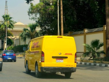 Kahire, Mısır, 31 Mayıs 2025: DHL minibüs bir paket teslimatı yapıyor, DHL uluslararası nakliye, kurye hizmetleri ve taşımacılık alanında uzmanlaşmış lojistik sektöründe küresel lider.
