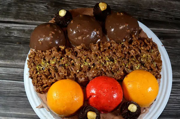 Dondurmalı pasta, üzerinde çikolata topu ve krema, karamel sosu, fındıklı çikolata parçaları, fındık, mango ve çilek topları, yaz ve tatil konsepti.