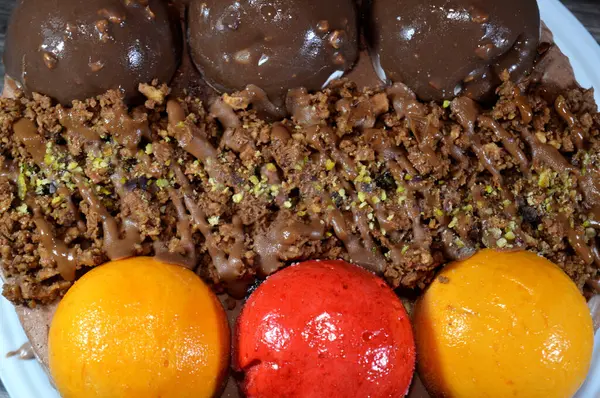 Dondurmalı pasta, üzerinde çikolata topu ve krema, karamel sosu, fındıklı çikolata parçaları, fındık, mango ve çilek topları, yaz ve tatil konsepti.