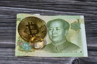Çin Yuan para banknot faturası ve Bitcoin fiziksel altın sikke, BTC 1. Merkezi olmayan kripto para birimi ve saf sarı bir yüzük, döviz kuru
