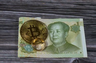 Çin Yuan para banknot faturası ve Bitcoin fiziksel altın sikke, BTC 1. Merkezi olmayan kripto para birimi ve saf sarı bir yüzük, döviz kuru