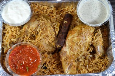 Orijinal tavuk ve renkli Basmati pilavı özel baharat, Daqos, yoğurt salatası ve tatlı sütlü sütlü sütlü puding karışımı bir düdüklü tencerede pişirildi.