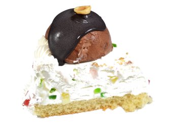 Üç köşeli bir parça Cassata dondurmalı kek vanilyalı, kremalı, sütlü, içi kurutulmuş meyveli, üzeri çikolata topu ve fındıklı ve fındıklı kek.