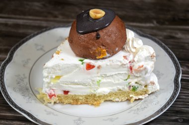 Üç köşeli bir parça Cassata dondurmalı kek vanilyalı, kremalı, sütlü, içi kurutulmuş meyveli, üzeri çikolata topu ve fındıklı ve fındıklı kek.