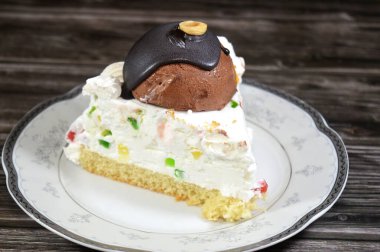 Üç köşeli bir parça Cassata dondurmalı kek vanilyalı, kremalı, sütlü, içi kurutulmuş meyveli, üzeri çikolata topu ve fındıklı ve fındıklı kek.