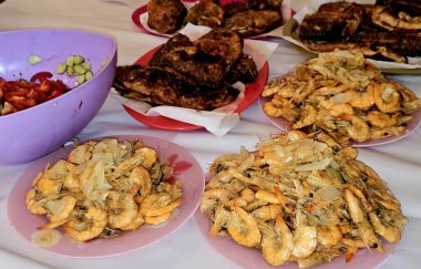 Kızarmış Nil tilapia balığının deniz mahsulleri Oreochromis Niloticus kızartması, kızgın buharda pişirilmiş kabuksuz gri karidesler ve soğan, sarımsaklı kimyon ve yeşil salatayla ızgara.