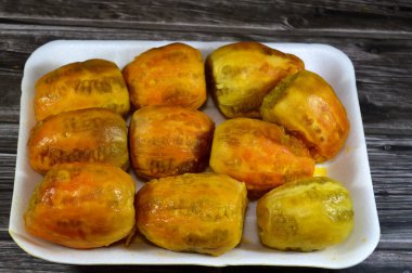 Ahşap zemin üzerinde izole edilmiş bir tabakta soyulmuş taze dikenli armut yığını, Opuntia, yaygın olarak dikenli armut, berber inciri, ton balığı meyvesi, sabra ve nopal olarak adlandırılan kaktüs, kaktüs, kaktüs türü.