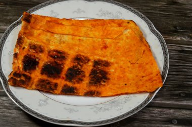 Katlanmış ince tortilla ekmeği bir tavada, ince, dairesel mayasız bir ekmek, masadan yapılmış ve buğday unundan yapılmış, pita düz ekmek tostu, öğünlerin yanında atıştırmalık olarak servis ediliyor.