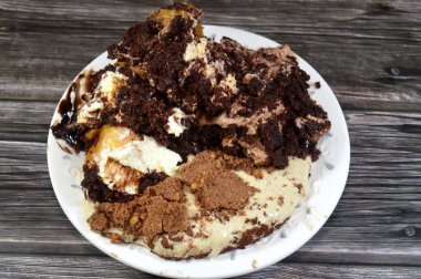 Kahveye batırılmış, koyu çikolata kaplı profiterol kremalı pasta, Fransız choux pastası, bisküvi ve çikolatalı kremayla doldurulmuş Tiramisu bayan parmak pastası (Savoiardi) tabağı.