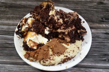 Kahveye batırılmış, koyu çikolata kaplı profiterol kremalı pasta, Fransız choux pastası, bisküvi ve çikolatalı kremayla doldurulmuş Tiramisu bayan parmak pastası (Savoiardi) tabağı.