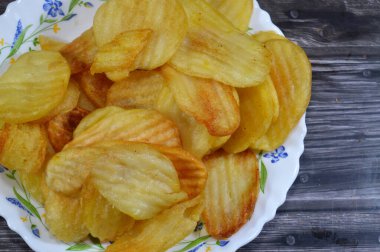 Patates cipsi, cips, ince patates dilimleri, kızartılmış, pişirilmiş, veya kızarana kadar havada kızartılmış, aperatif, meze veya meze olarak servis edilmiş, temel cips pişti ve tuzlandı, bazıları diğer tatlarla birlikte.