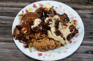 Kahveye batırılmış, koyu çikolata kaplı profiterol kremalı pasta, Fransız choux pastası, bisküvi ve çikolatalı kremayla doldurulmuş Tiramisu bayan parmak pastası (Savoiardi) tabağı.