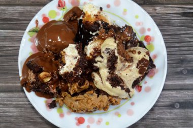 Kahveye batırılmış, koyu çikolata kaplı profiterol kremalı pasta, Fransız choux pastası, bisküvi ve çikolatalı kremayla doldurulmuş Tiramisu bayan parmak pastası (Savoiardi) tabağı.