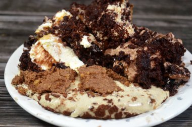 Kahveye batırılmış, koyu çikolata kaplı profiterol kremalı pasta, Fransız choux pastası, bisküvi ve çikolatalı kremayla doldurulmuş Tiramisu bayan parmak pastası (Savoiardi) tabağı.