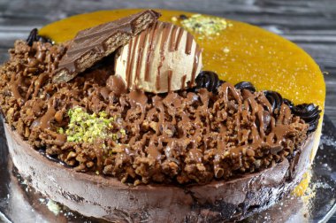 Dondurmalı pasta, üzerinde çikolata parçacıkları ve krema ve sos ile kaplı, fıstıklı çikolata parçaları, yarım mango ve yarım çikolata, yaz ve tatil konsepti.