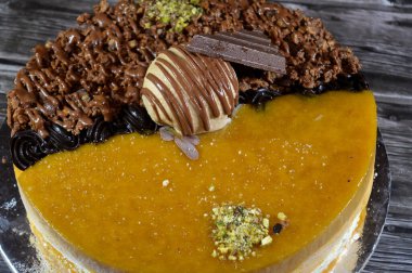 Dondurmalı pasta, üzerinde çikolata parçacıkları ve krema ve sos ile kaplı, fıstıklı çikolata parçaları, yarım mango ve yarım çikolata, yaz ve tatil konsepti.