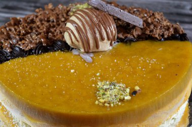 Dondurmalı pasta, üzerinde çikolata parçacıkları ve krema ve sos ile kaplı, fıstıklı çikolata parçaları, yarım mango ve yarım çikolata, yaz ve tatil konsepti.