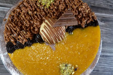 Dondurmalı pasta, üzerinde çikolata parçacıkları ve krema ve sos ile kaplı, fıstıklı çikolata parçaları, yarım mango ve yarım çikolata, yaz ve tatil konsepti.