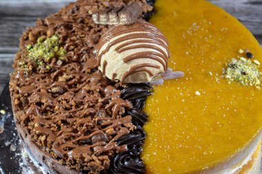 Dondurmalı pasta, üzerinde çikolata parçacıkları ve krema ve sos ile kaplı, fıstıklı çikolata parçaları, yarım mango ve yarım çikolata, yaz ve tatil konsepti.