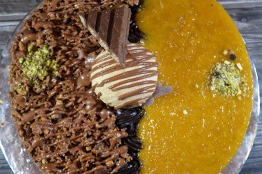 Dondurmalı pasta, üzerinde çikolata parçacıkları ve krema ve sos ile kaplı, fıstıklı çikolata parçaları, yarım mango ve yarım çikolata, yaz ve tatil konsepti.