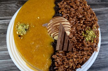 Dondurmalı pasta, üzerinde çikolata parçacıkları ve krema ve sos ile kaplı, fıstıklı çikolata parçaları, yarım mango ve yarım çikolata, yaz ve tatil konsepti.